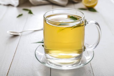 Bir fincan sıcak aromatik çay ve yeşil çay yaprakları.