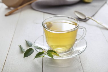 Bir fincan sıcak aromatik çay ve yeşil çay yaprakları.