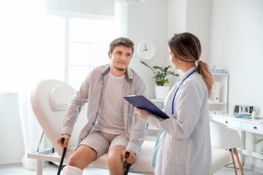Kırık bacaklı genç bir adam klinikteki doktoru ziyaret ediyor.