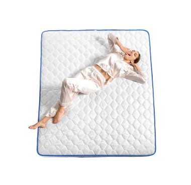 Genç bir kadın beyaz arka planda şiltede yatıyor.