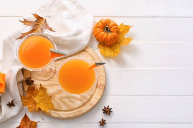 Beyaz ahşap zemin üzerinde balkabağı turtası martinisi ile sonbahar kompozisyonu