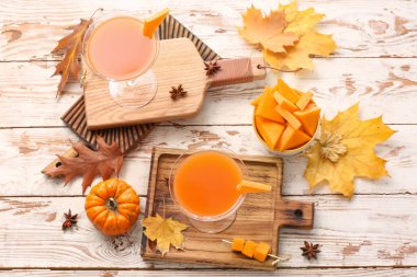 Beyaz ahşap zemin üzerinde balkabağı turtası martinisi ile sonbahar kompozisyonu