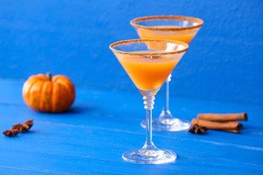 Renkli ahşap arka planda balkabaklı martini bardakları