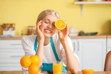 Mutfakta portakal suyu ve meyve suyu olan güzel bir kadın.
