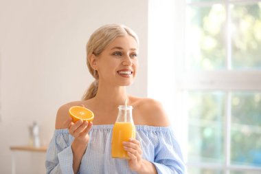 Güzel genç bayan evde portakal suyu içiyor.
