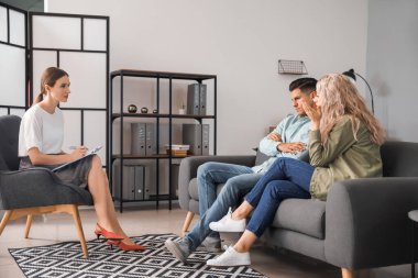 Ofiste genç bir çiftle çalışan psikolog.