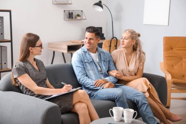 Ofiste genç bir çiftle çalışan psikolog.