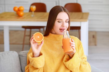Güzel genç bayan evde portakal suyu içiyor.
