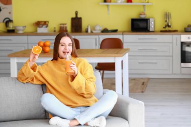 Güzel genç bayan evde portakal suyu içiyor.