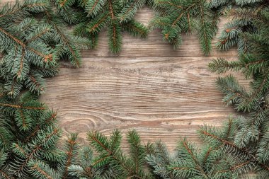 Ahşap zemin üzerinde Noel ağacı dallarından yapılmış çerçeve