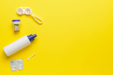 Renk arkaplan üzerinde kontak lens, çözüm ve cımbız içeren kaplar