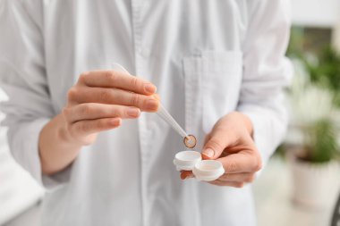 Klinikte çözeltisi olan konteynırdan lensi çıkaran kadın