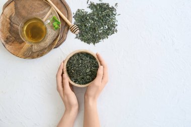 Kuru çay yapraklı kadın ışık masasında kasede