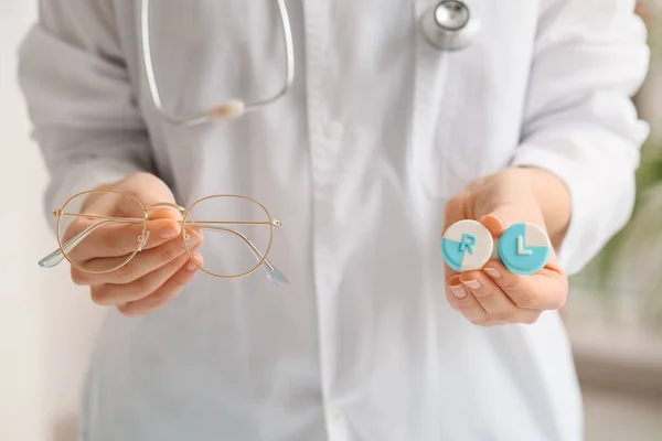 Woman holding glasses and contact lens case in clinic