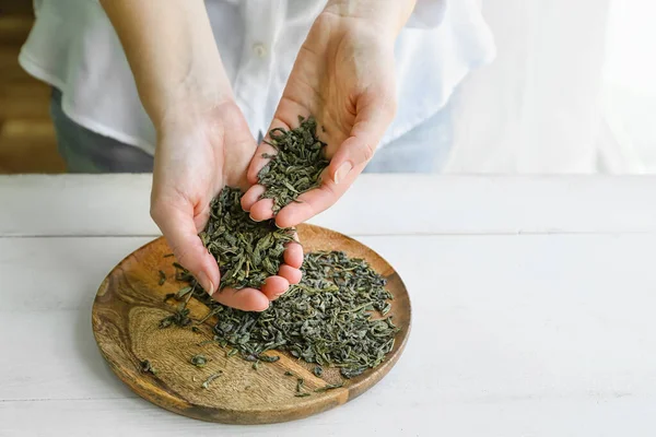 テーブルの上に乾燥した緑茶の葉を持つ女性 — ストック写真