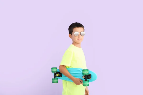 スタイリッシュなサングラスと色の背景にスケートボードとかわいい男の子 — ストック写真