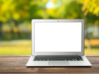 Dışarıdaki ahşap masada boş ekranlı dizüstü bilgisayar.