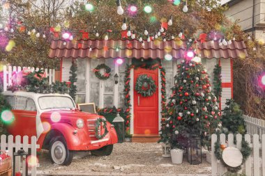 Araba ve köknar ağacı Noel için dekore edilmiş evin yanında.