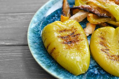 Ahşap masada ızgara dolma biberli tabak.