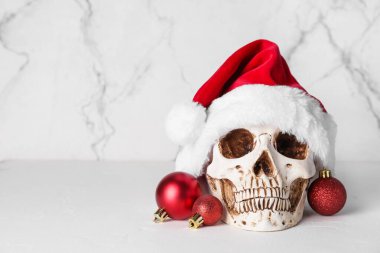 Noel Baba şapkası insan kafatası ve beyaz arka planda Noel topları