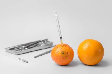 Şırıngalı taze portakallar ve arka planda cerrahi aletler. Göğüs büyütme konsepti