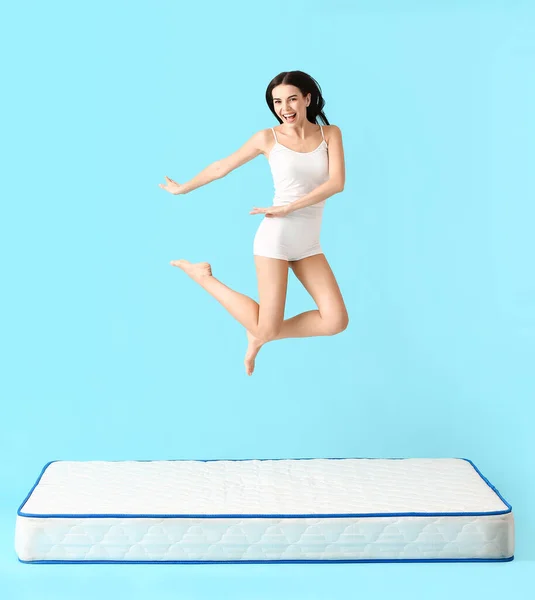 Young Woman Jumping Mattress Color Background — Stock Photo, Image