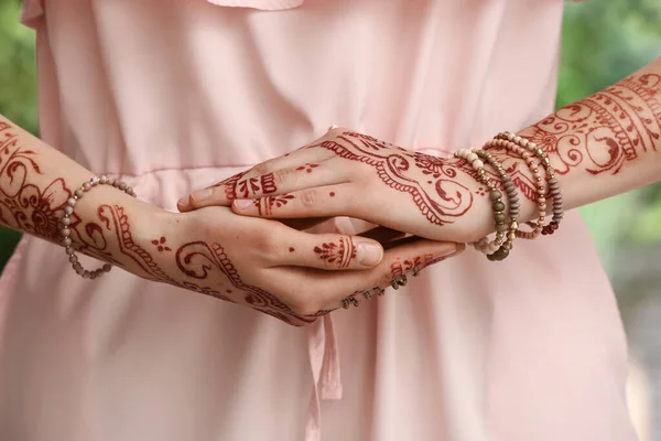 Beautiful woman with henna tattoo on her hands outdoors, closeup