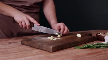 Masada taze sarımsak kesen kadın, yakın plan.
