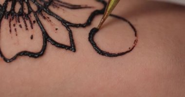 Güzeller güzeli bir kadın kuaförde dövme yaptırıyor.