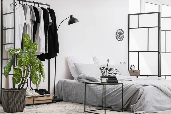 Interior of stylish bedroom with clothes rack