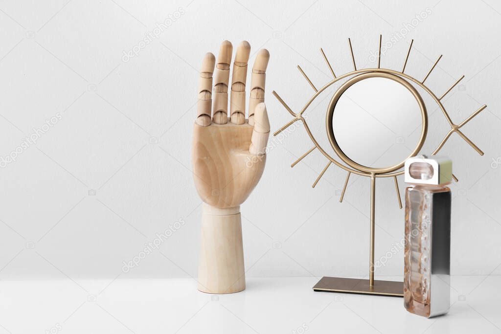 Wooden hand with mirror on light background