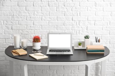 Tuğla duvarın yanında dizüstü bilgisayarı olan şık bir iş yeri