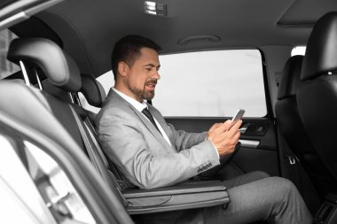 Modern arabadaki cep telefonuyla başarılı bir iş adamı.