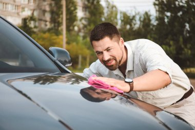 Yakışıklı adam dışarıda arabasını yıkıyor.