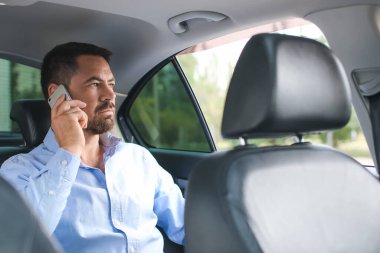 Modern arabada telefonla konuşan yakışıklı bir adam.