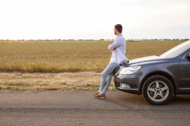 Modern arabanın yanında yakışıklı bir adam.