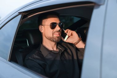 Modern arabada cep telefonuyla konuşan yakışıklı bir adam.