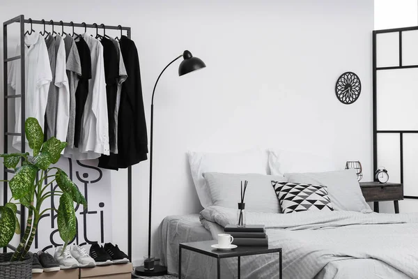 Interior of stylish bedroom with clothes rack