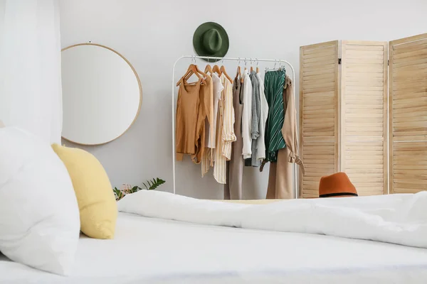 Interior of stylish bedroom with clothes rack