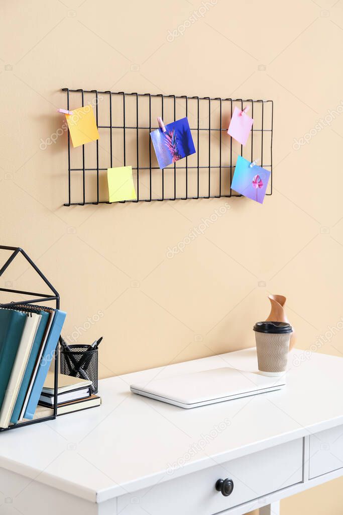 Stylish workplace with moodboard near color wall