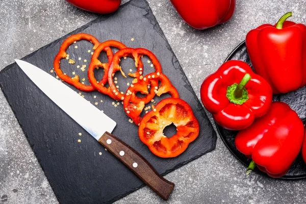 Kırmızı dolma biber ve siyah arka planda bıçak.