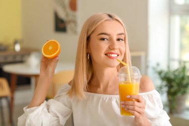 Güzel genç bayan evde taze portakal suyu içiyor.