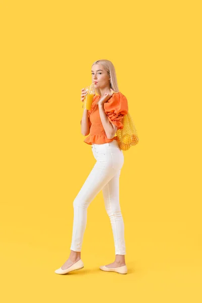 美丽的年轻女子 有橙子和果汁的颜色背景 — 图库照片