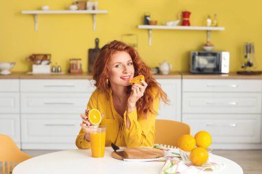 Güzel genç bayan mutfakta taze portakal suyu yapıyor.