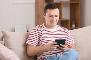 Genç adam evde e-kitap okuyor.