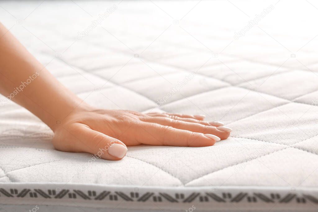 Woman touching soft orthopedic mattress, closeup