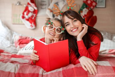 Mutlu kız ve annesi Noel arifesinde karavanda kitap okuyorlar.