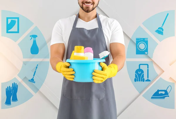 灰色の背景に電源とクリーニングサービスのアイコンを持つ男性清掃員 — ストック写真
