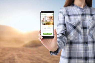 İnternette cep telefonu rezervasyon odası olan genç bir kadın.