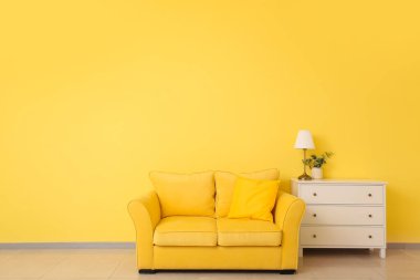 Oda duvarının yanında rahat bir kanepe ve çekmeceler.